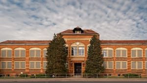 Een foto van een klassiek schoolgebouw met schaapjeswolken op de achtergrond en twee grote sparren Een foto van de webpagina van Pi Network (PI), een populaire altcoin uit de top 20 die in 2025 werd gelanceerd