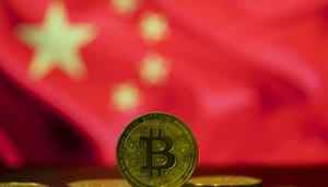 Een bitcoin (BTC) munt op de voorgrond, met op de achtergrond de vlag van China Een bitcoin (BTC) munt op de voorgrond, met op de achtergrond de vlag van China