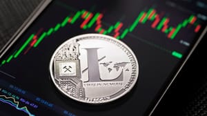 Een afbeelding van een litecoin (LTC) munt op een mobiele telefoon met een grafiek op een crypto exchange