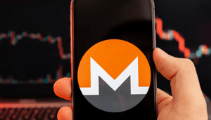 Monero logo op mobiel met koersgrafiek Monero logo op mobiel met koersgrafiek