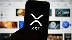 Een afbeelding van het XRP logo op een mobiele telefoon met op de achtergrond media gerelateerd aan Ripple en hun munt XRP Een afbeelding van het XRP logo op een mobiele telefoon met op de achtergrond media gerelateerd aan Ripple en hun munt XRP