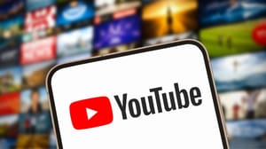 Een afbeelding van het logo van YouTube met op de achtergrond een reeks video's op een scherm Een afbeelding van het logo van YouTube met op de achtergrond een reeks video's op een scherm