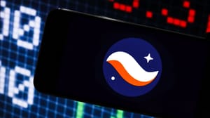 Een afbeelding van het logo van cryptomunt starknet op een mobiele telefoon met op de achtergrond marktdata en grafieken Een afbeelding van het logo van cryptomunt starknet op een mobiele telefoon met op de achtergrond marktdata en grafieken