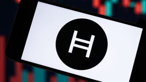 Een afbeelding van het logo van Hedera (HBAR) met een grafiek van de koers op de achtergrond Een afbeelding van het logo van Hedera (HBAR) met een grafiek van de koers op de achtergrond