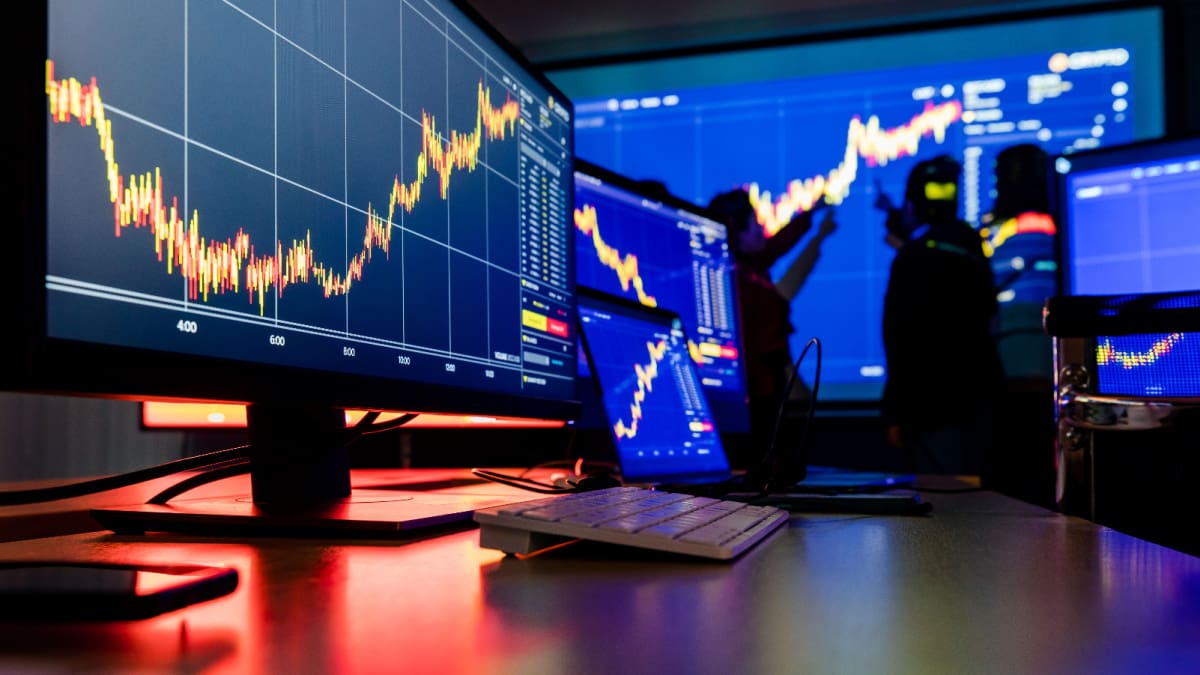 Een afbeelding van een kantoortje van een handelaar in aandelen of crypto's, met veel candle charts op verschillende schermen met data Een afbeelding van een kantoortje van een handelaar in aandelen of crypto's, met veel candle charts op verschillende schermen met data