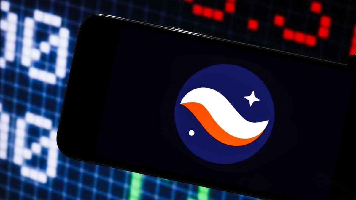 Een afbeelding van het logo van cryptomunt starknet op een mobiele telefoon met op de achtergrond marktdata en grafieken Een afbeelding van het logo van cryptomunt starknet op een mobiele telefoon met op de achtergrond marktdata en grafieken